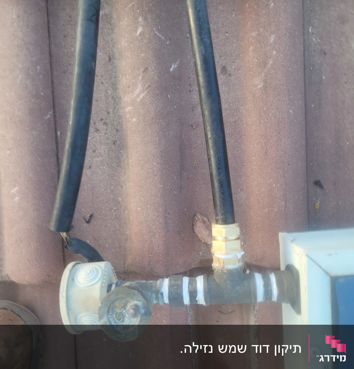 צינור שחור מחובר לדוד שמש על גג רעפים